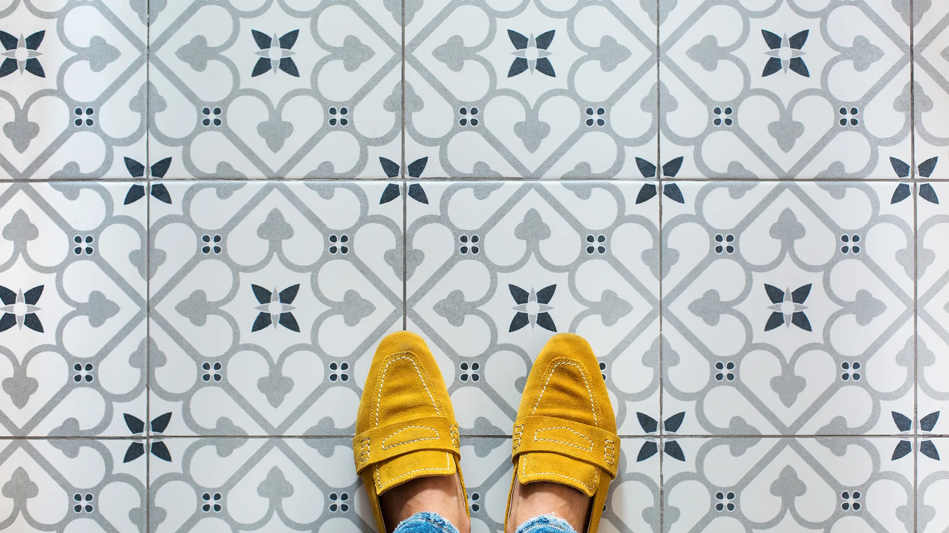 Female legs, feet in yellow shoes on a mosaic tile floor. Top view, flat lay selfie on a vintage seamless background, copy space